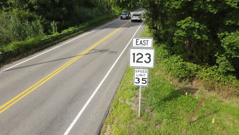 Long-Aerial-shot-of-cars-passing-road-signs,-loopable-static-shot
