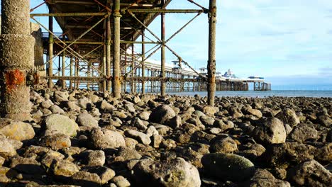 Under-weathered-worn-Llandudno-pier-landmark-support-pillars-at-low-tide-dolly-right-shot