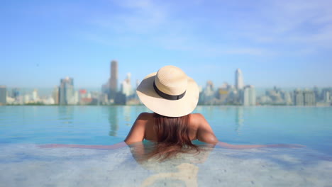 Back-View-of-Stylish-Woman-in-Infinity-Rooftop-Pool-With-Stunning-View-of-Modern-Cityscape-in-Background