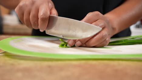 Chopping-fresh-green-chives-to-add-to-a-family,-organic,-vegan-recipe---slow-motion-side-view-isolated-close-up