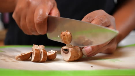 Slicing-raw-Shiitake-mushrooms-with-a-chef's-knife-on-a-cutting-board---side-view-close-up-in-slow-motion