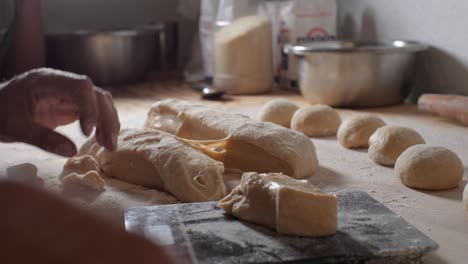 Young-Latino-worker-in-a-Mexican-bakery-measuring,-cutting,-weighing-on-scales-and-forming-loaves-of-bread,-slowmotion,-organic-and-glutenfree-bread