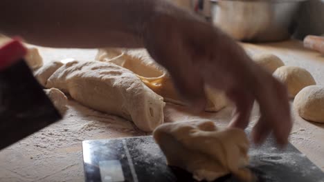 Skilled-baker-cutting-bread-dough-into-loaves-to-be-baked,-small-home-based-bakery-business-during-COVID-19-pandemic