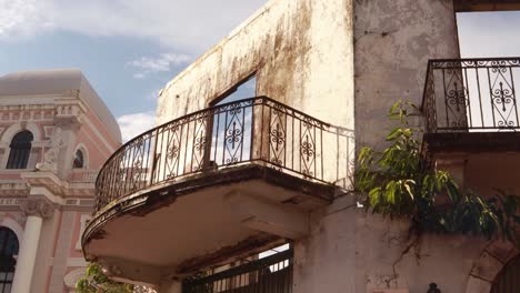 Balcony-of-old-abandoned-building-structure-with-the-interior-demolished-and-the-paint-peeling-from-walls,-vegetation-growing-from-façade-of-historic-construction-in-Panama-Casco-Viejo-during-the-day
