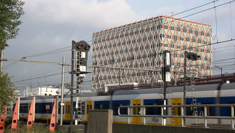 Train-Crossing-In-Gouda-Train-Station-And-The-Building-Of-City-Hall-In-Amsterdam,-Netherlands
