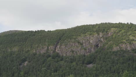 Clouds-Moving-Over-The-Green-Forest-And-Rocky-Cliffs-During-Daytime