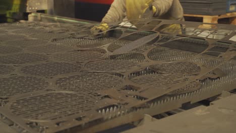 Close-up-shot-of-industrial-worker-taking-pieces-of-flat-sheet-metal-at-factory