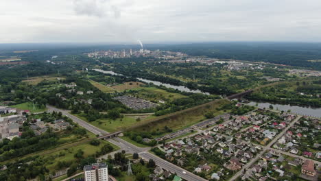 Apartment-buildings-of-Jonava-and-Achema-chemical-industrial-factory-in-horizon-during-rainfall,-aerial-view