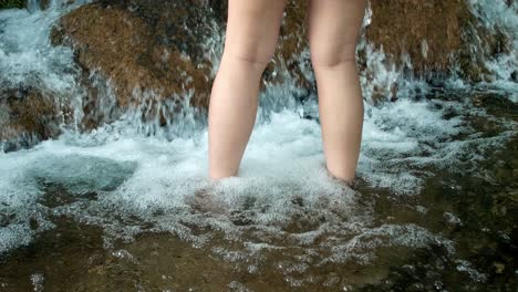 Woman-using-her-legs-to-soak-in-a-natural-waterfall