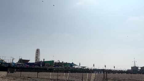 Panning-shot-of-Santa-Monica-Pier-with-amusement-park-and-sand-beach,-California