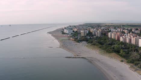 Aerial-view-of-sandy-beach-with-umbrellas,gazebos-and-town