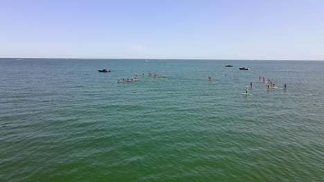 Aerial-sliding-view-showing-Standup-Paddle-Boarding-race-event-on-waters-of-Rexhame-beach,-Marshfield