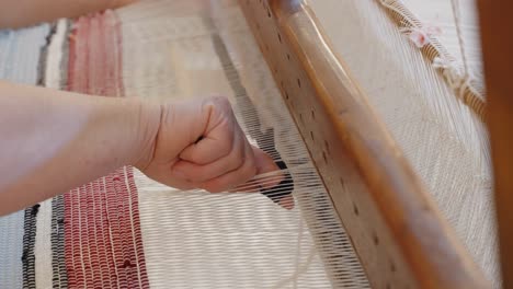 Close-up-of-a-woman-using-a-traditional-loom-to-weave-fabric