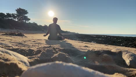 Kerl-Meditiert-An-Einem-Ruhigen-Strand-Bei-Sonnenuntergang