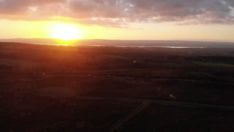 Luftschwenk-Links-Mit-Blick-Auf-Woodbury-Common-In-Devon-England-Mit-Einem-Dramatischen-Goldenen-Sonnenuntergang