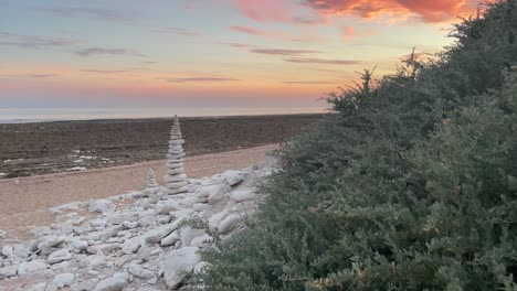 Pan-view-of-pyramid-built-of-white-stones-on-a-deserted-beach-at-sunset