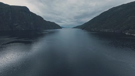 Vast-lake-water-with-rocky-mountains-around,-aerial-drone-view