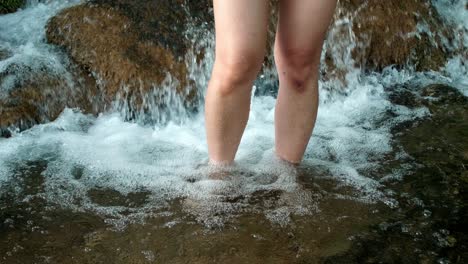 Woman-using-her-legs-to-soak-in-a-natural-waterfall