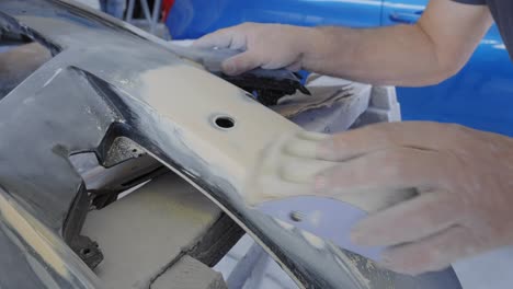 Close-up-of-sanding-a-car-bumper-by-hand-to-prepare-for-painting-and-restoration
