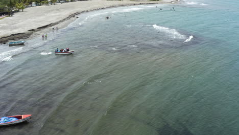 AERIAL---Boats-and-people-on-the-beach,-Monte-Rio,-Dominican-Republic,-forward-shot