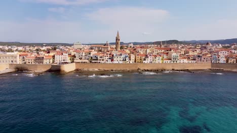 Drone-clip-over-the-blue-ocean-with-the-scenic-town-of-Alghero-in-Sardinia,-Italy-extending-along-the-background