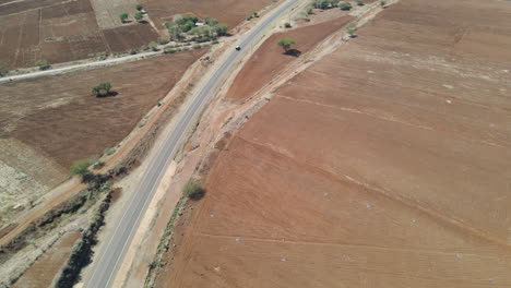 Aerial-dolly-of-a-car-driving-over-a-lonesome-road-through-a-dry-landscape-in-rural-Kenya