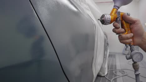Close-up-of-painting-a-silver-car-with-a-professional-air-spray-gun