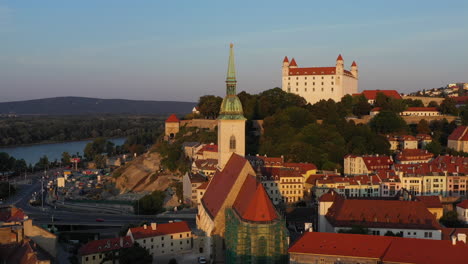 Wide-drone-shot-with-the-Saint-Martin's-Cathedral-in-the-foreground-and-the-Bratislava-Castle-in-the-background-in-Bratislava-Slovakia-during-golden-hour