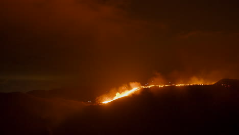 Bright-glowing-hot-lava-flowing-through-the-landscape-at-night--Wide