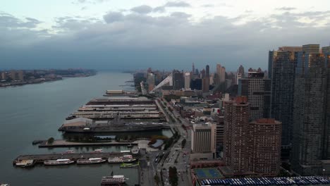 Aerial-view-of-piers-and-skyscrapers-in-Hell's-Kitchen,-Manhattan,-cloudy-evening-in-New-York---pan,-drone-shot