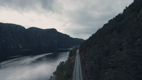 Mountain-landscape-with-lake-water-and-asphalt-road,-aerial-drone-view