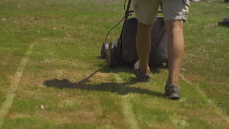 Back-view-of-unrecognizable-man-cutting-grass-with-push-lawn-mower