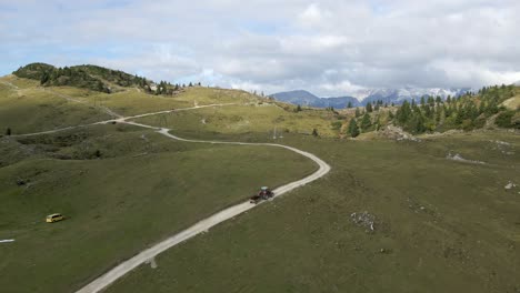 Tractor-driving-on-dirt-road-during-summer-in-Velika-Planina,-aerial