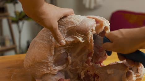 Cutting-turkey-meat-with-kitchen-knife-on-wooden-cut-board