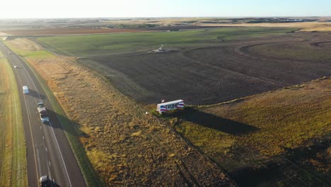 Large-Donald-Trump-2024-Campaign-Sign-in-Rural-Midwest-Kansas-Displayed-along-I-70-East-and-West-Interstate-Painted-on-Large-Truck-on-Trailer,-Farm-land-and-Open-Field,-Aerial-Dronve-Flying