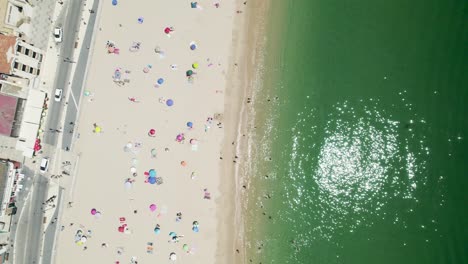 People-bathing-and-sunbathing-on-beach-of-Sesimbra,-Portugal