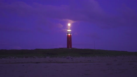 Large-red-metal-lighthouse-located-on-the-coast-illuminated-warning-any-vessel-of-the-presence-of-land-recorded-while-it-was-getting-dark
