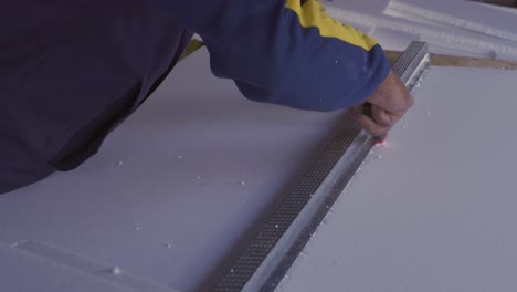 Close-up-man-hand-cutting-foam-board-with-cutter-in-4K
