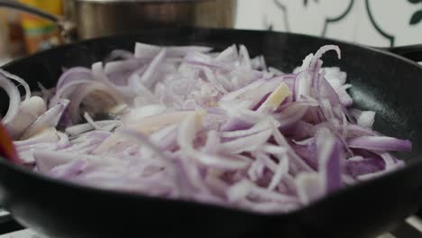 Frying-caramelized-onion-inside-black-frying-pan-on-gas-stove