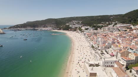 Aerial-backwards-view-of-long-and-beautiful-beach-with-its-bay-in-Sesimbra