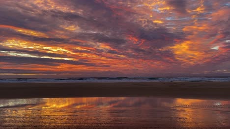 Erstaunlicher-Und-Dramatischer-Sonnenaufgang-Oder-Sonnenuntergang-Auf-Australiens-Fraser-Island,-Mit-Einer-Atemberaubenden-Orange--Und-Goldpalette-Wie-Auf-Einem-ölgemälde,-Das-Sich-In-Wasser-Gespiegelt-Am-Strand-Widerspiegelt