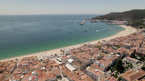 Aerial-view-Sesimbra-Beautiful-Coastline,-red-tiled-buildings-waterfront,-Clear-water-Beach