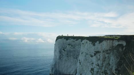 4K-Landscape-panoramic-shot-of-a-group-of-people-walking-to-the-edge-of-a-cliff-on-a-sunny-day