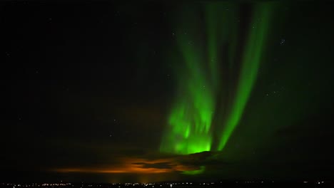 Wide-shot-of-bright-lighting-Northern-Lights-at-dark-sky-over-Cityscape-of-Reykjavik,Iceland