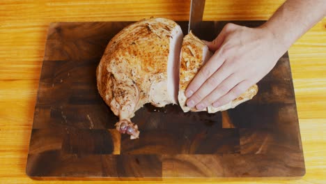 Top-view-of-Chef-cutting-freshly-grilled-turkey-meat-on-wooden-cut-board