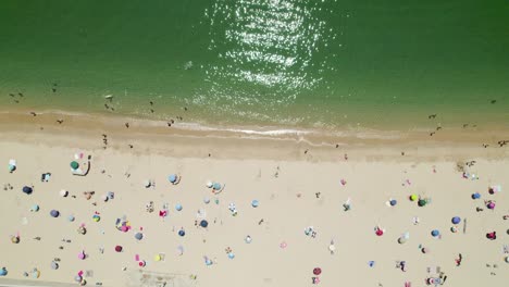 Luftbild-Von-Oben-Nach-Unten-Entlang-Des-Wunderschönen-Sandstrandes,-Des-Grünen-Wassers-Und-Der-Bunten-Sonnenschirme