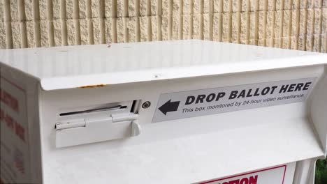 Young-Minority-Black-Man-Votes-by-Dropping-Mail-in-Ballot-Letter-in-Slot-at-Official-Voting-Box-with-Drop-Ballot-Here-Sign