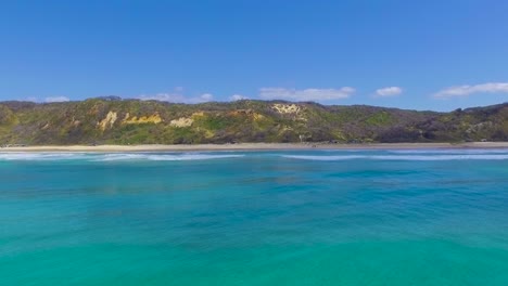 View-from-high-over-the-brilliant-blue-green-ocean,-looking-back-towards-the-rugged-and-stunning-coastline-of-Australia's-Fraser-Island,-K'Gari