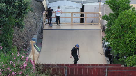 Young-skaters-riding-on-backyard-ramp-doing-tricks,-aerial-view