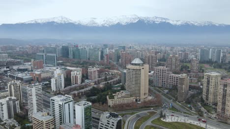 Aerial-orbit-around-main-roundabout-with-skyscrapers-in-Santiago,-Chile-with-the-andes-mountains-on-the-back